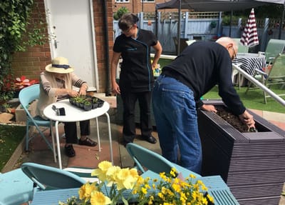 Residents and staff gardening outdoors at Rosewood Villa