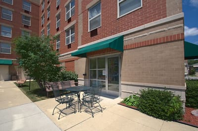 Outdoor seating area with tables near the facility entrance