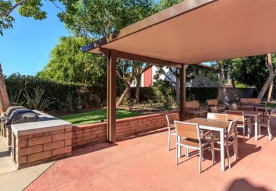 Outdoor shaded seating area with tables and grill