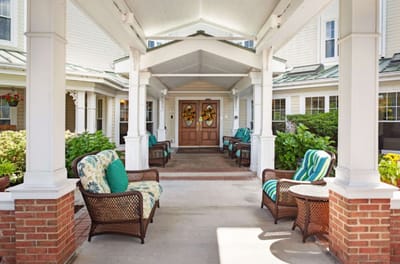 Covered entrance with seating area and greenery