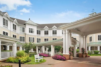 Exterior view of a senior living facility with gardens and seating