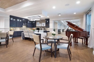 Bright common area with a grand piano and dining tables