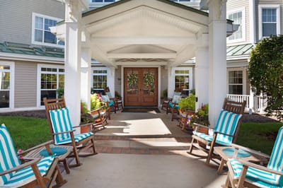 Exterior view of entrance with rocking chairs and lush greenery