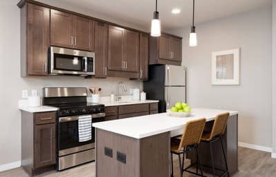 Modern kitchen area with stainless steel appliances and bar stools