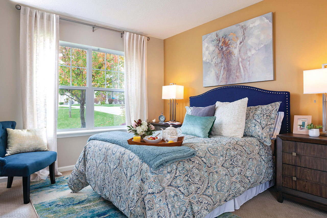 Cozy resident room with a neatly made bed and decorative pillows