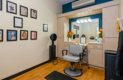 A hair salon area with styling chair and framed magazine covers