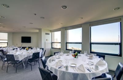 Dining area set up for a meal with windows overlooking the water