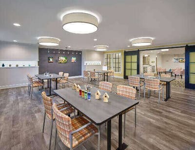 Bright common area with tables and chairs in a senior living facility