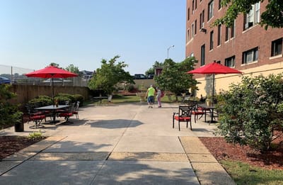 Outdoor courtyard with red umbrellas and residents walking