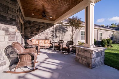 Seating area on a covered patio with a stone wall