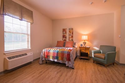 A cozy resident room with a bed and chair