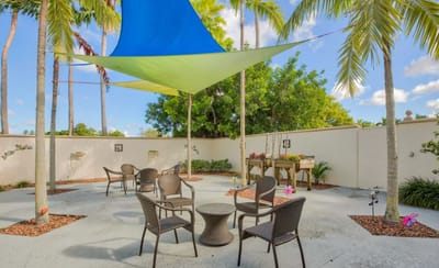 Outdoor seating area with shaded tables and palm trees