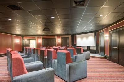 Interior view of a movie theater room with red chairs