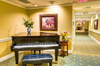 Interior view of a hallway with a piano and flowers