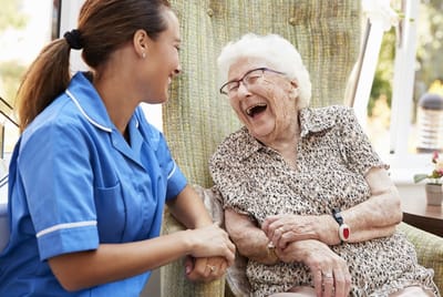 A caregiver laughing with an elderly resident
