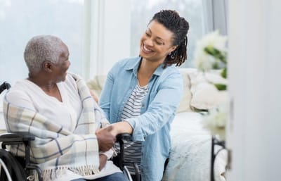 A caregiver smiling at a resident in a comfortable room