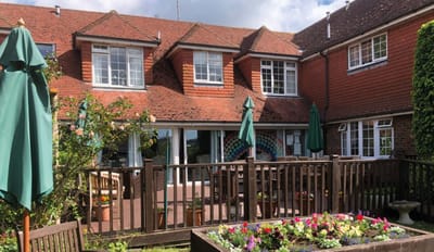 Exterior view of a care home with a garden and seating area
