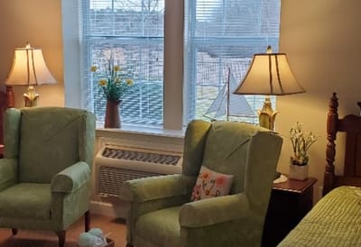 Cozy resident room with green chairs and natural light