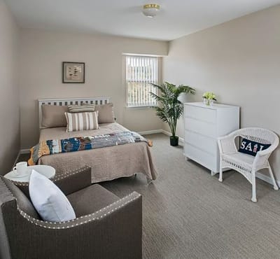 Brightly decorated resident room with a bed and chair