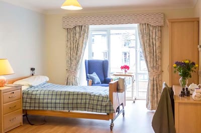 Private resident room with bed and armchair