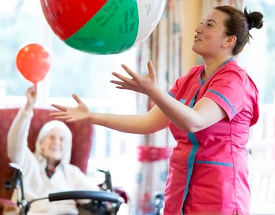 Staff member engaging residents with a beach ball activity