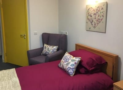 Cozy private resident room with a bed and chair
