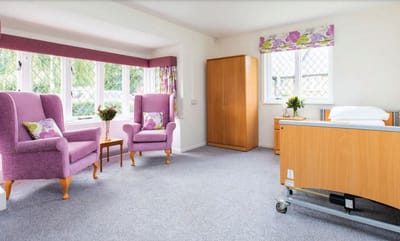 A spacious resident room with purple chairs and natural light