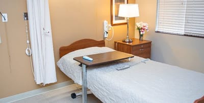 A private resident room with a bed and lamp