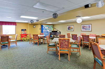 Bright common area with dining tables and a piano
