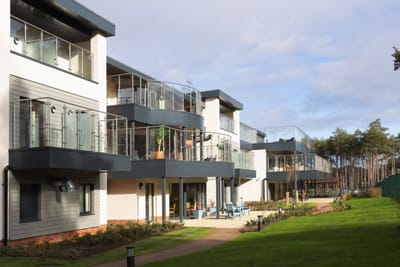 Modern assisted living facility with balconies and landscaped gardens.