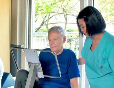 Resident using exercise equipment with staff assistance