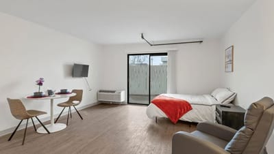 A bright private room with a bed and dining area