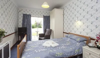Cozy bedroom with floral wallpaper and a view of a garden