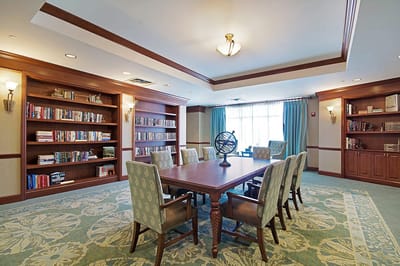 A nicely appointed common area with bookshelves and a large table