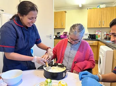 Staff helping a resident bake in a kitchen