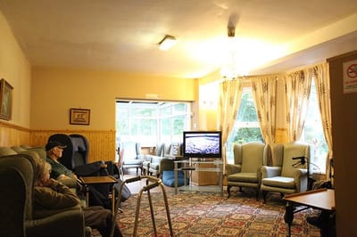 Residents in a cozy common area watching TV