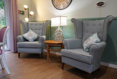 Cozy common area with high-backed chairs and a lamp