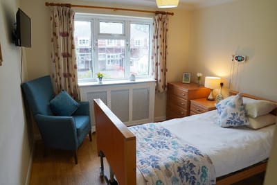 A cozy resident room with a bed and chair
