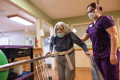 Hacienda Oaks Nursing & Rehabilitation Center, Nursing Home in Beeville, TX — Senior resident assisted by nurse in rehabilitation center