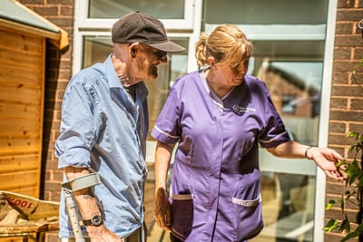 Staff member assisting resident in a garden area