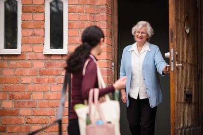 A smiling resident greeting a staff member at the door