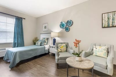Brightly lit interior room with bed and seating area