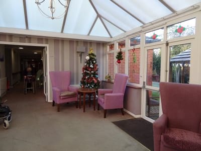 Bright sunroom with festive decorations and comfortable seating
