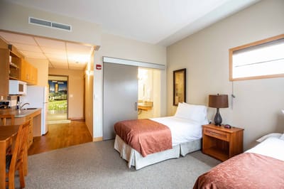 A cozy resident room with two beds and a kitchenette