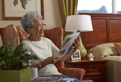 Resident reading a newspaper in a cozy room