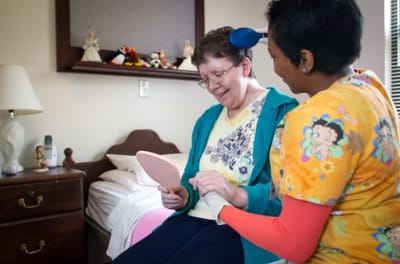 Staff assisting a resident with a mirror in a private room