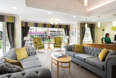 Bright common area with comfortable seating and a staff member