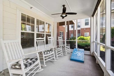 Screened porch with rocking chairs and cornhole game