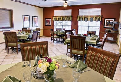 Bright dining room with neatly set tables and flowers