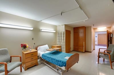 A patient room with a hospital bed and chairs